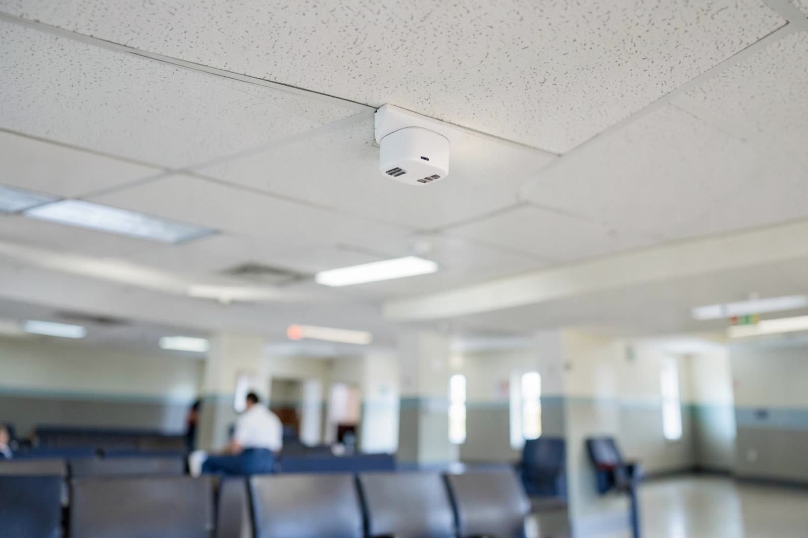 Punto de acceso inalámbrico montado en el techo de un pasillo hospitalario.